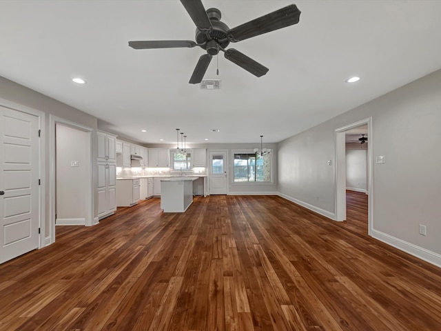 unfurnished living room with ceiling fan with notable chandelier and dark hardwood / wood-style flooring