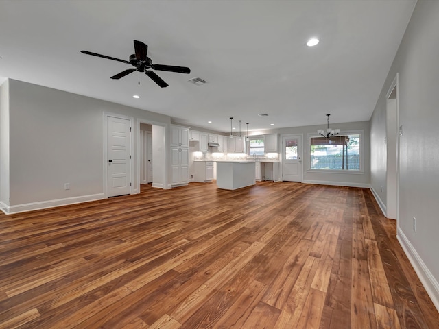 unfurnished living room featuring wood-type flooring and ceiling fan with notable chandelier