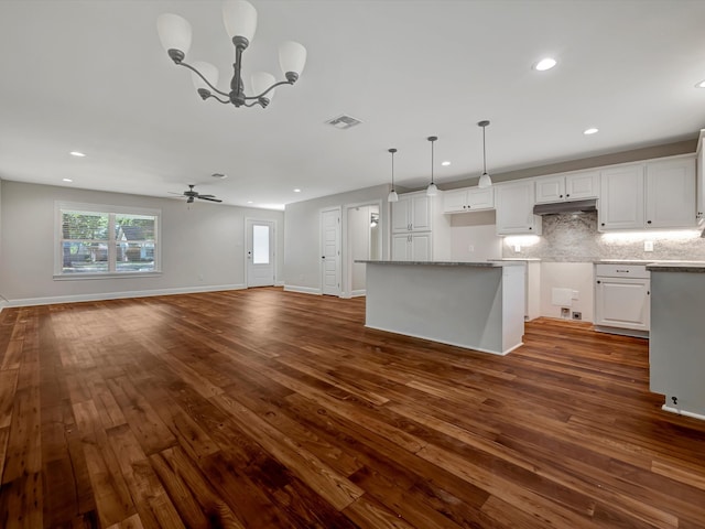 kitchen with dark hardwood / wood-style floors, backsplash, decorative light fixtures, white cabinetry, and ceiling fan with notable chandelier