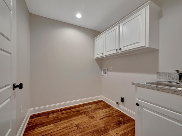 laundry area featuring sink, washer hookup, light hardwood / wood-style floors, and cabinets