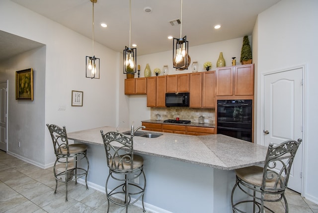 kitchen with a center island with sink, sink, black appliances, and a kitchen bar