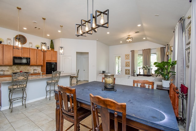 dining area with light tile patterned flooring and vaulted ceiling