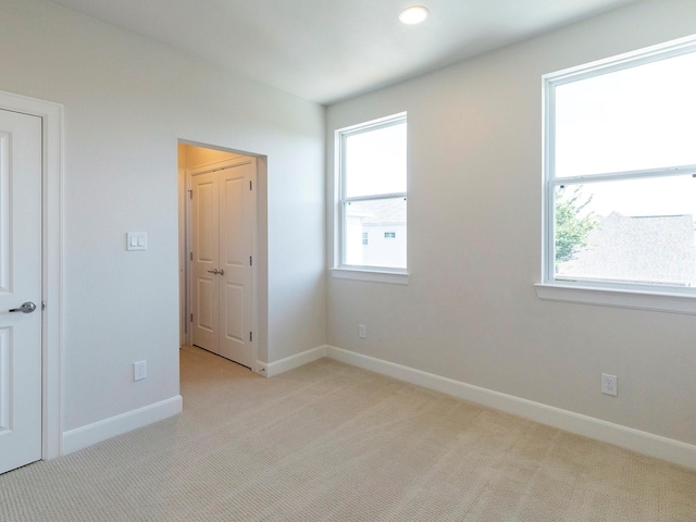 unfurnished bedroom featuring light carpet and multiple windows