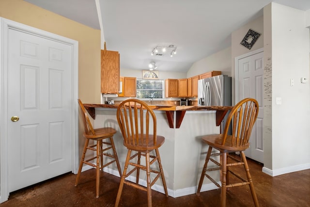 kitchen featuring a kitchen breakfast bar, vaulted ceiling, stainless steel refrigerator with ice dispenser, and kitchen peninsula