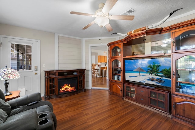 living room with a textured ceiling, dark wood-type flooring, and ceiling fan