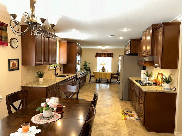 kitchen featuring light stone countertops, appliances with stainless steel finishes, backsplash, and sink