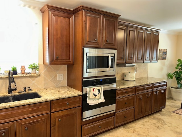 kitchen featuring backsplash, sink, stainless steel appliances, and ornamental molding