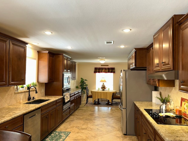 kitchen featuring backsplash, light stone countertops, sink, and appliances with stainless steel finishes