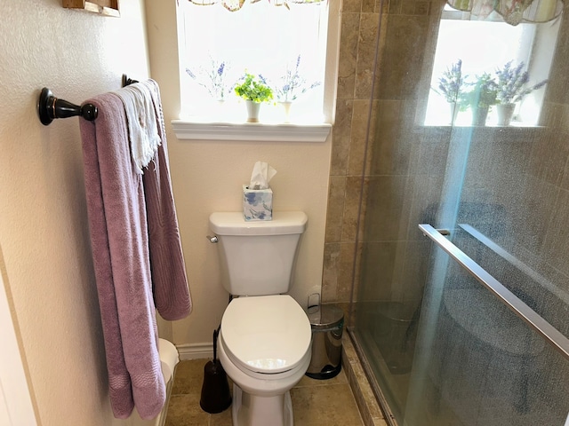 bathroom with tile patterned floors, toilet, and a shower with shower door