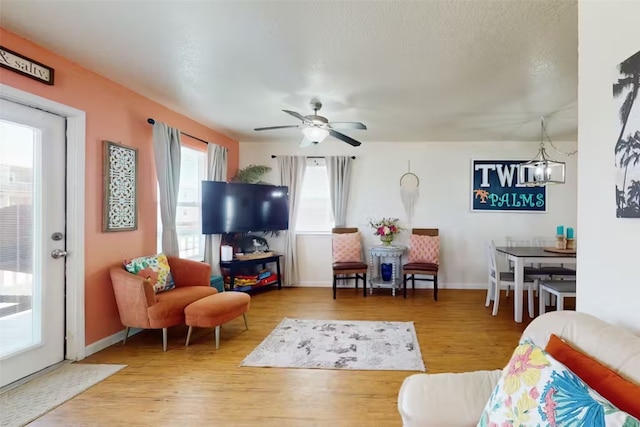 living room with hardwood / wood-style floors, a wealth of natural light, and ceiling fan with notable chandelier