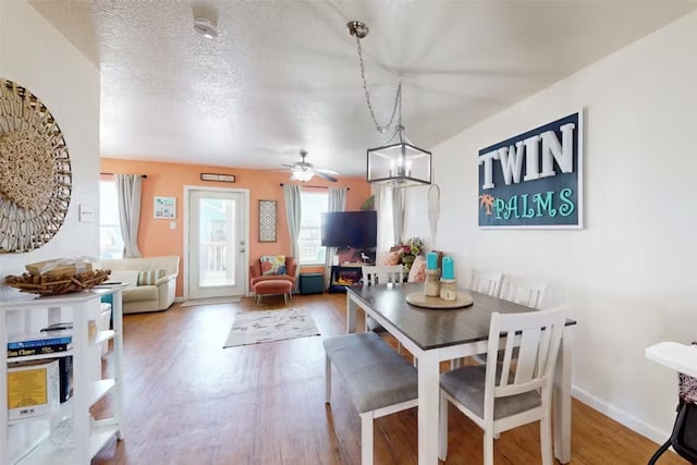 dining area with a textured ceiling, hardwood / wood-style flooring, and ceiling fan with notable chandelier