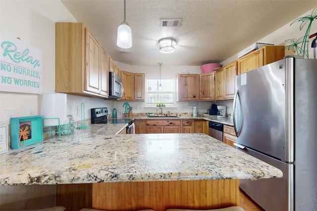 kitchen with stainless steel appliances, sink, a breakfast bar, kitchen peninsula, and decorative light fixtures