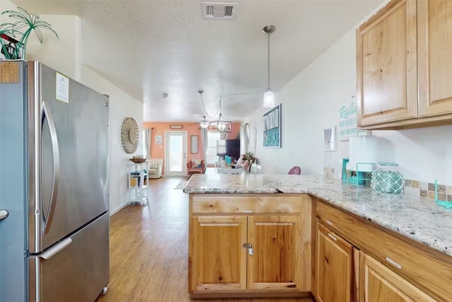 kitchen with light hardwood / wood-style floors, kitchen peninsula, hanging light fixtures, a chandelier, and stainless steel refrigerator