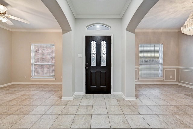 tiled entrance foyer with ornamental molding, a healthy amount of sunlight, and ceiling fan