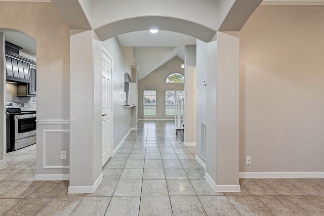 hallway with high vaulted ceiling and light tile patterned floors