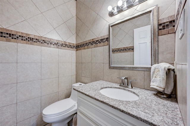 bathroom featuring vanity, toilet, and tile walls