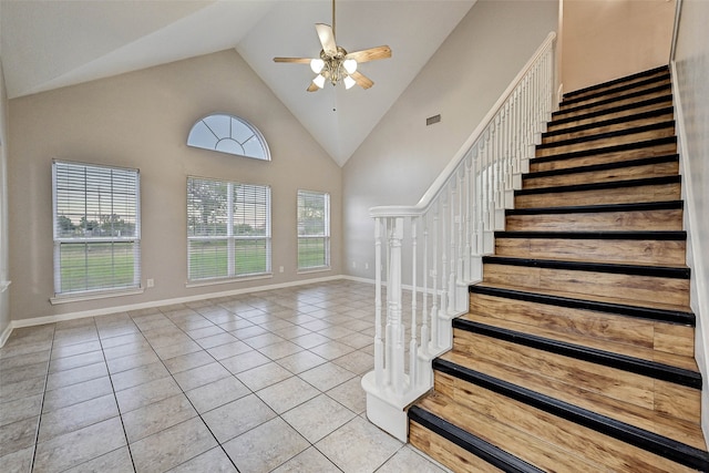 staircase with ceiling fan, high vaulted ceiling, and tile patterned floors