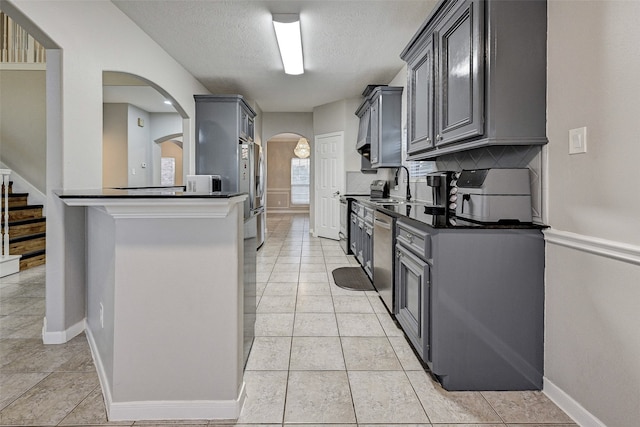 kitchen featuring tasteful backsplash, appliances with stainless steel finishes, a textured ceiling, gray cabinets, and sink