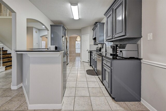 6530 Fm 3180 W, Mont Belvieu, TX 77523 - kitchen with arched walkways, dark countertops, a textured ceiling, baseboards, and backsplash