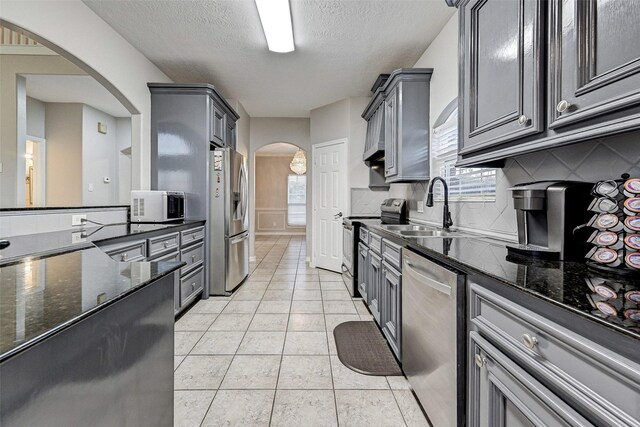6530 Fm 3180 W, Mont Belvieu, TX 77523 - kitchen featuring appliances with stainless steel finishes, a sink, gray cabinets, arched walkways, and tasteful backsplash