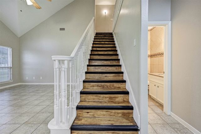 stairs featuring ceiling fan, high vaulted ceiling, and tile patterned flooring