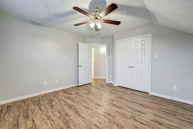 unfurnished bedroom with lofted ceiling, ceiling fan, a textured ceiling, light hardwood / wood-style floors, and a closet