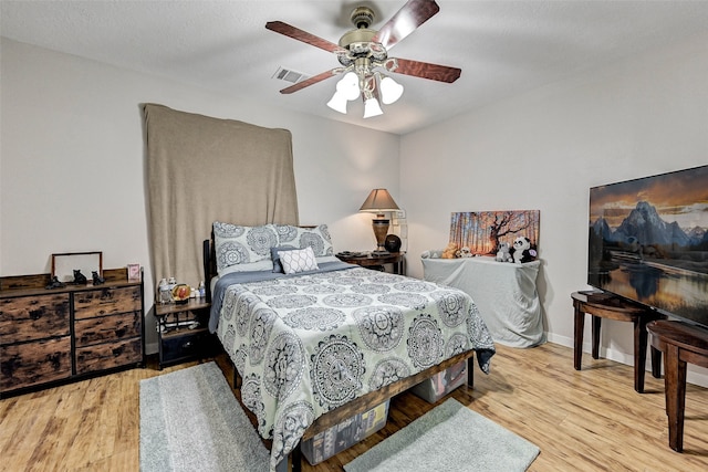 bedroom with a textured ceiling, light wood-type flooring, and ceiling fan