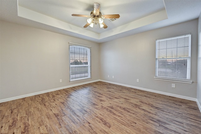 spare room with hardwood / wood-style floors, ceiling fan, and a raised ceiling