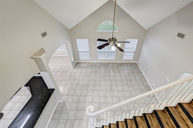 unfurnished living room with light tile patterned floors, high vaulted ceiling, and ceiling fan