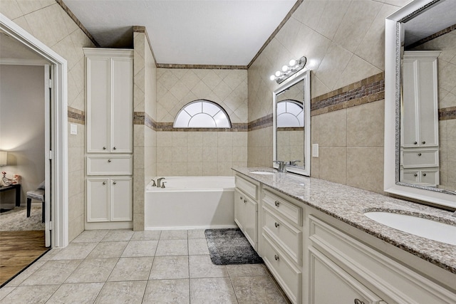 bathroom with a bathtub, tile walls, vanity, crown molding, and tile patterned flooring