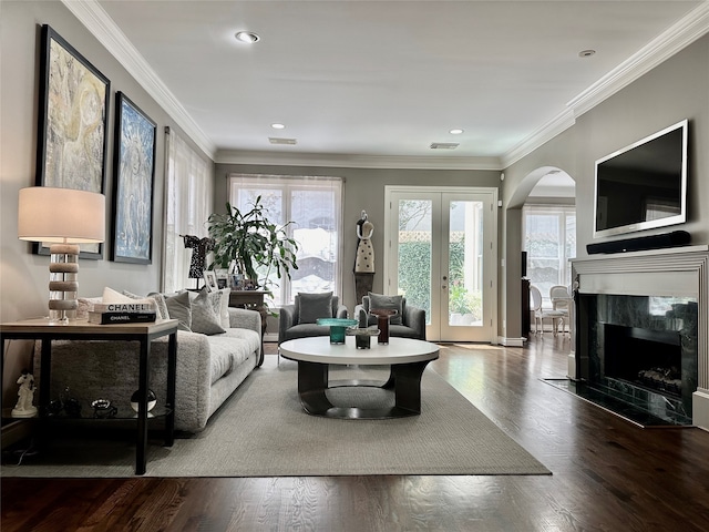 living room featuring a tile fireplace, ornamental molding, wood-type flooring, and plenty of natural light