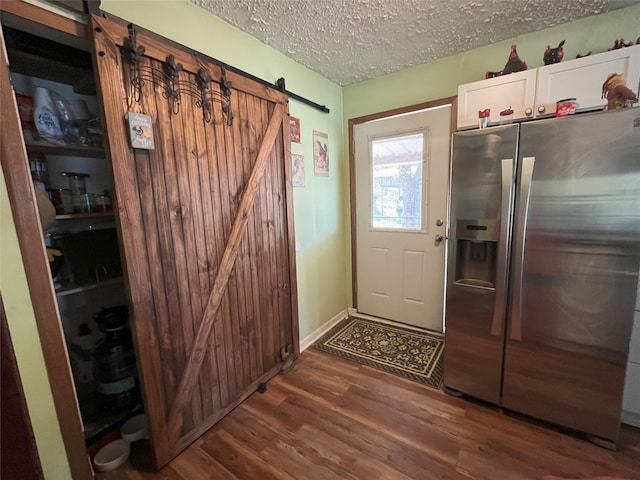 entryway featuring a barn door, dark hardwood / wood-style flooring, and a textured ceiling