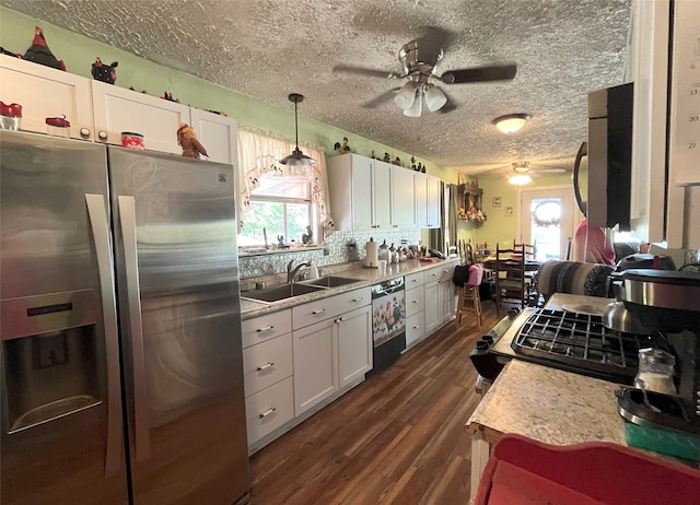 kitchen with appliances with stainless steel finishes, decorative light fixtures, white cabinetry, and a healthy amount of sunlight