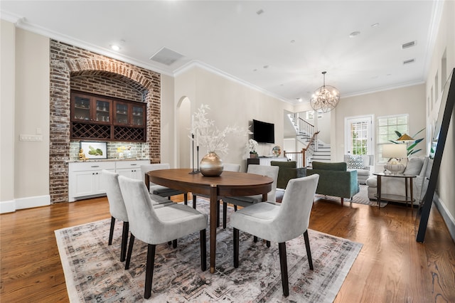 dining space featuring ornamental molding, a chandelier, and dark hardwood / wood-style flooring