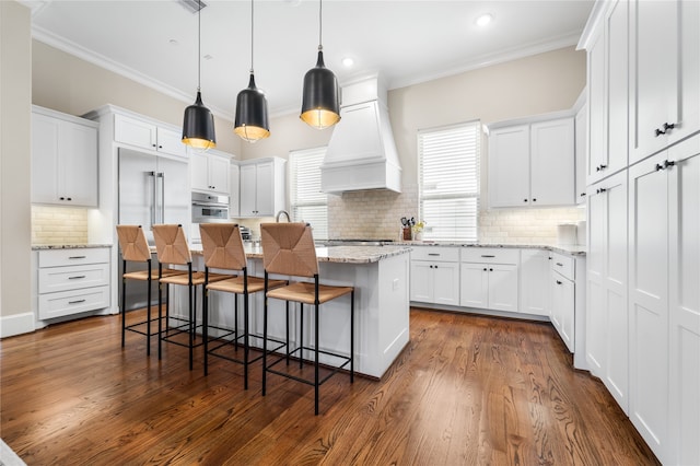 kitchen featuring a kitchen island, white cabinets, custom range hood, and stainless steel appliances