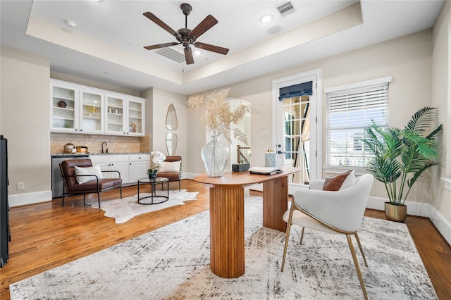 sitting room with hardwood / wood-style floors, sink, a tray ceiling, and ceiling fan