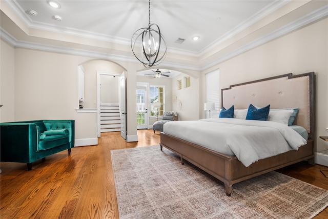 bedroom with crown molding, hardwood / wood-style flooring, and a chandelier