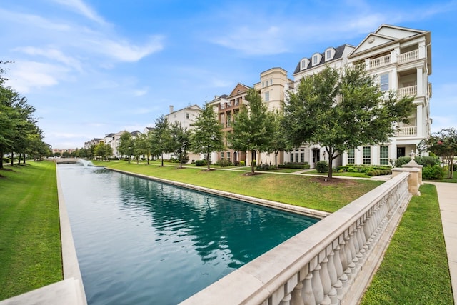 view of pool with a water view and a lawn