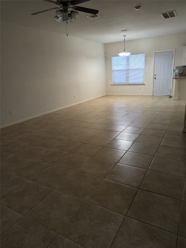 tiled spare room featuring ceiling fan with notable chandelier