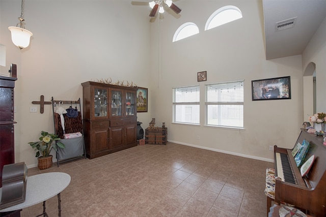 living area with a high ceiling, light tile patterned flooring, and ceiling fan