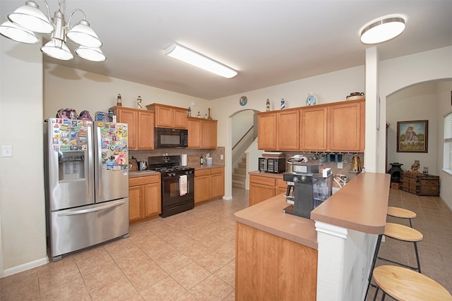 kitchen with black appliances, kitchen peninsula, a kitchen bar, backsplash, and pendant lighting