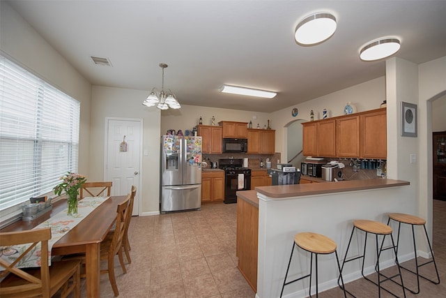 kitchen featuring decorative backsplash, black appliances, kitchen peninsula, and decorative light fixtures