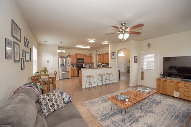 living room featuring light tile patterned floors and ceiling fan with notable chandelier