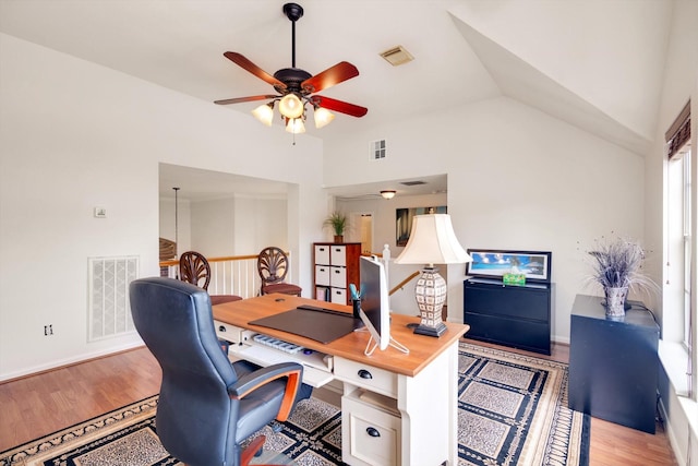 home office with ceiling fan, vaulted ceiling, and light hardwood / wood-style flooring