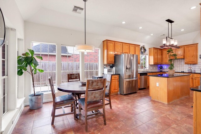 kitchen with pendant lighting, sink, tasteful backsplash, a kitchen island, and stainless steel appliances