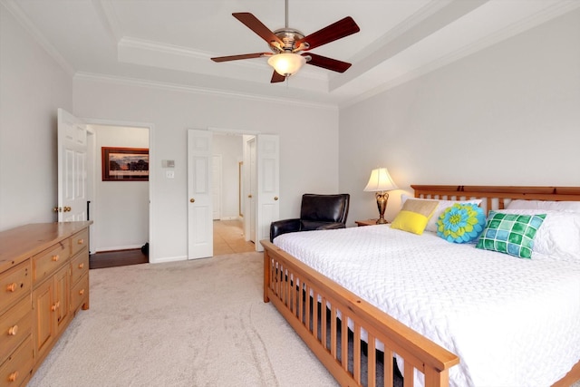 carpeted bedroom with a tray ceiling, ceiling fan, and crown molding