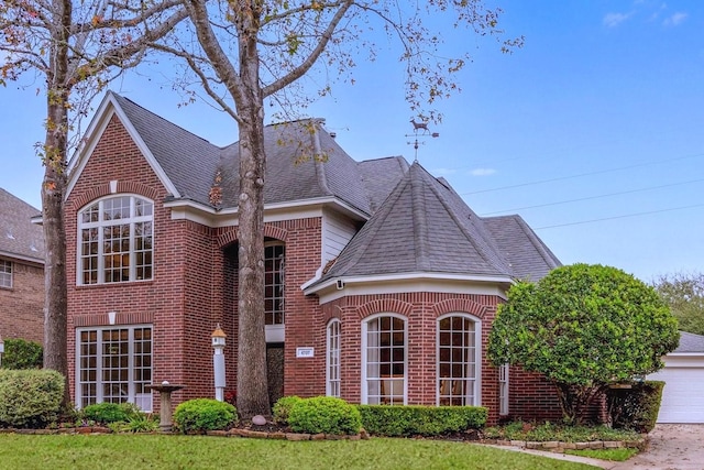 view of front facade featuring a garage, brick siding, and roof with shingles