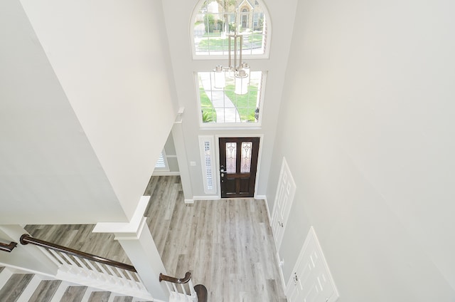 entrance foyer featuring a towering ceiling, light wood-type flooring, and a notable chandelier