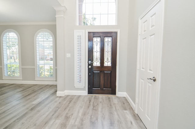 entryway with ornamental molding, decorative columns, and light hardwood / wood-style floors