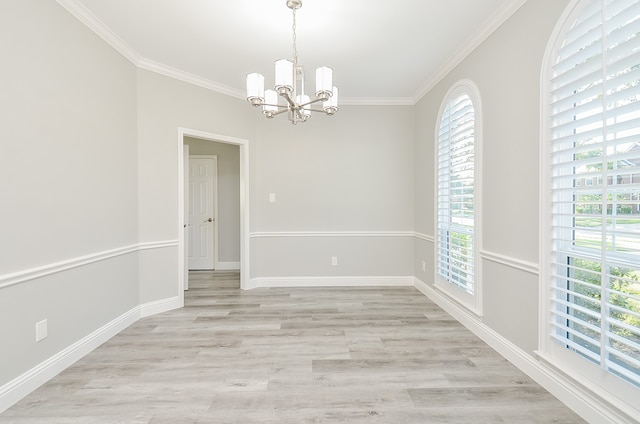 spare room featuring light wood-type flooring, a chandelier, and ornamental molding